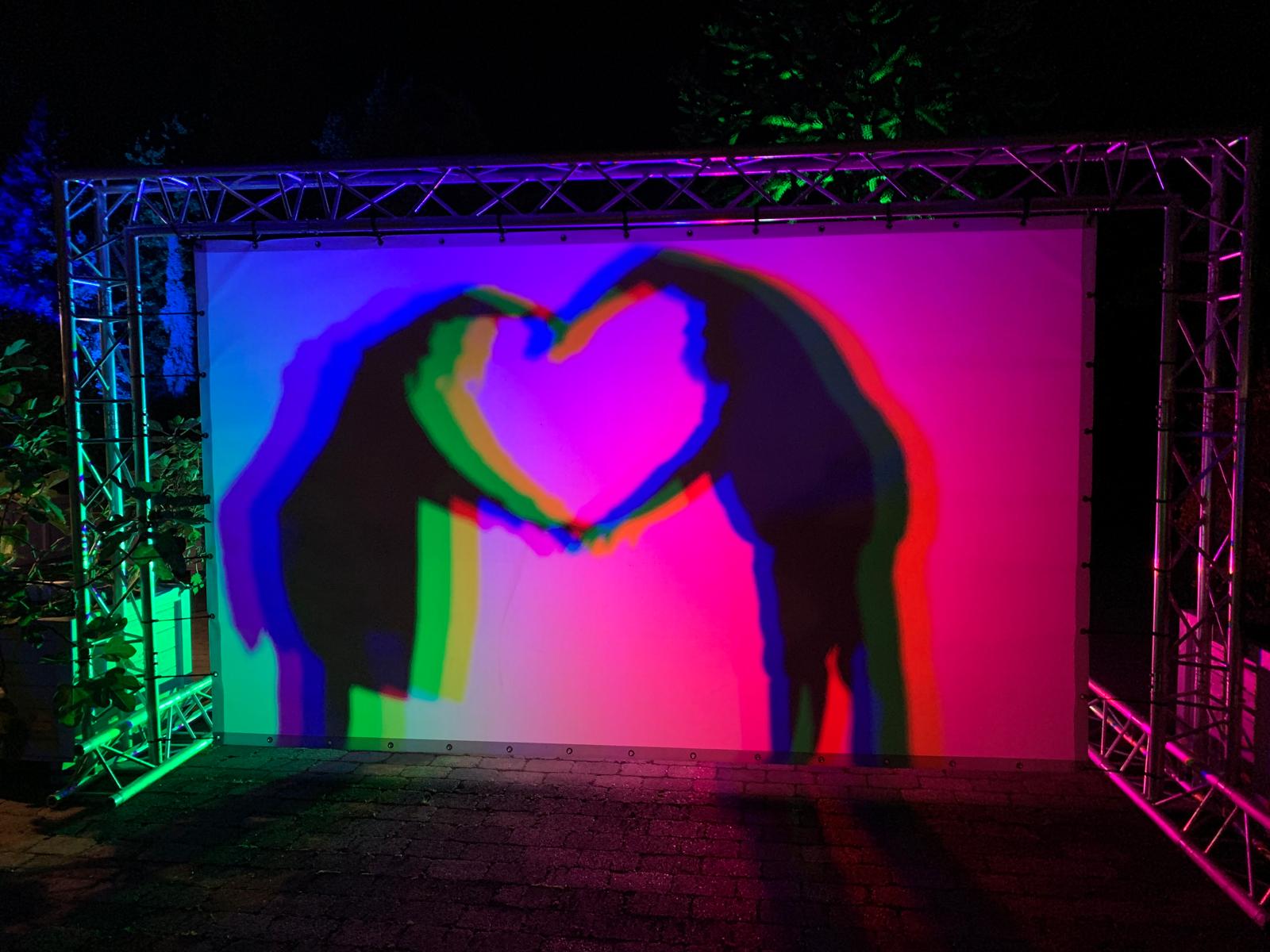 Farbige Schatten zweier Menschen vor einer Leinwand